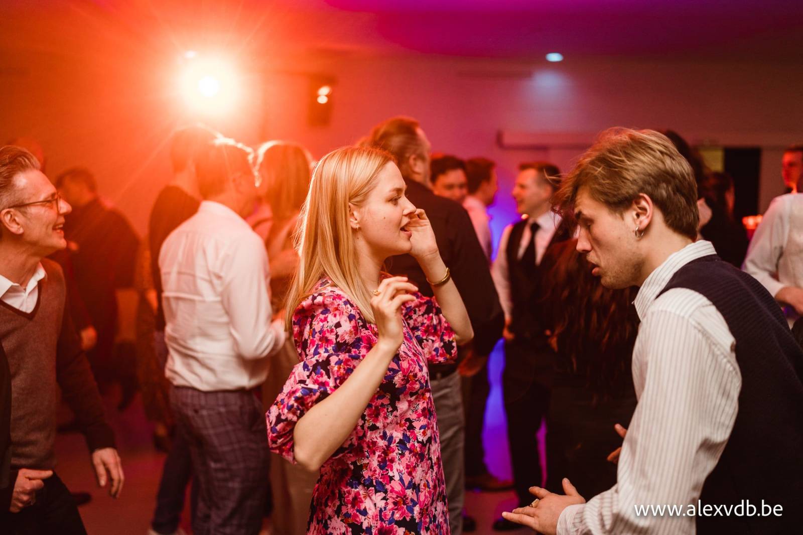 Gasten dansen in warm rood licht